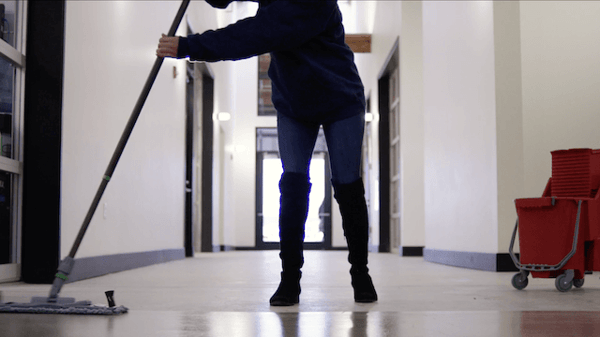 Cleansolution employee mopping in a business hallway